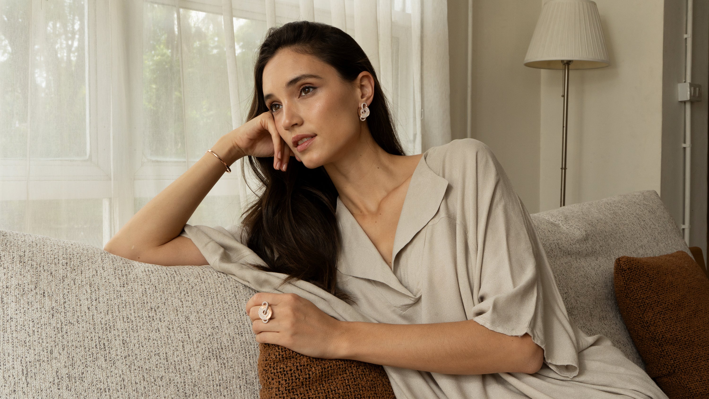 Woman sitting on a couch in a living room setting wearing High Jewelry